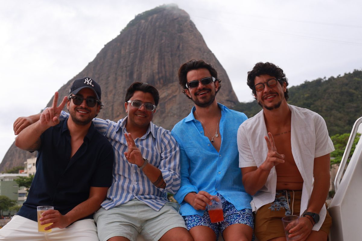 Grupo de amigos a bordo com drinks, com o Pão de Açúcar ao fundo